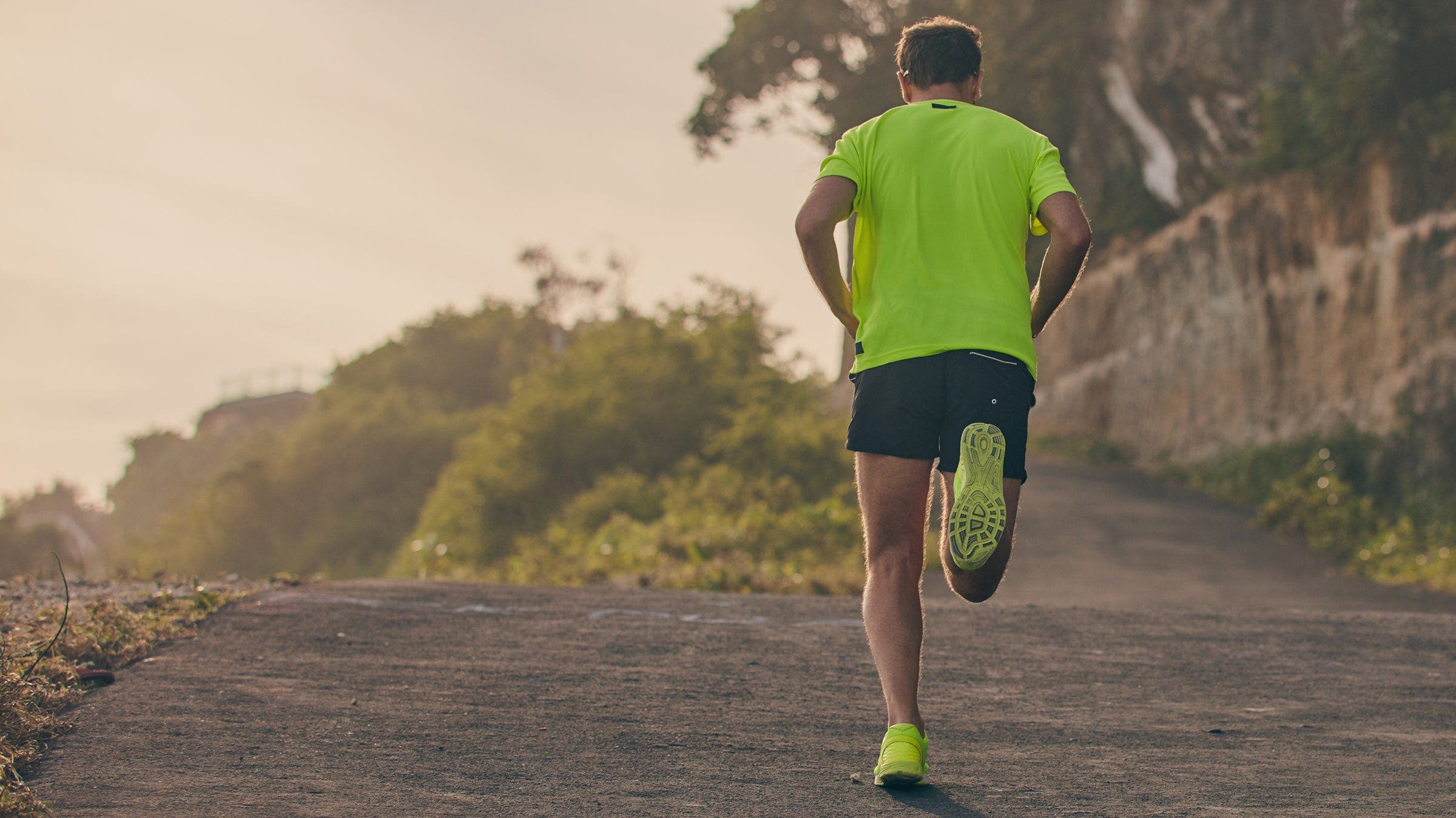 Man running on an uphill in suburb mountain road.