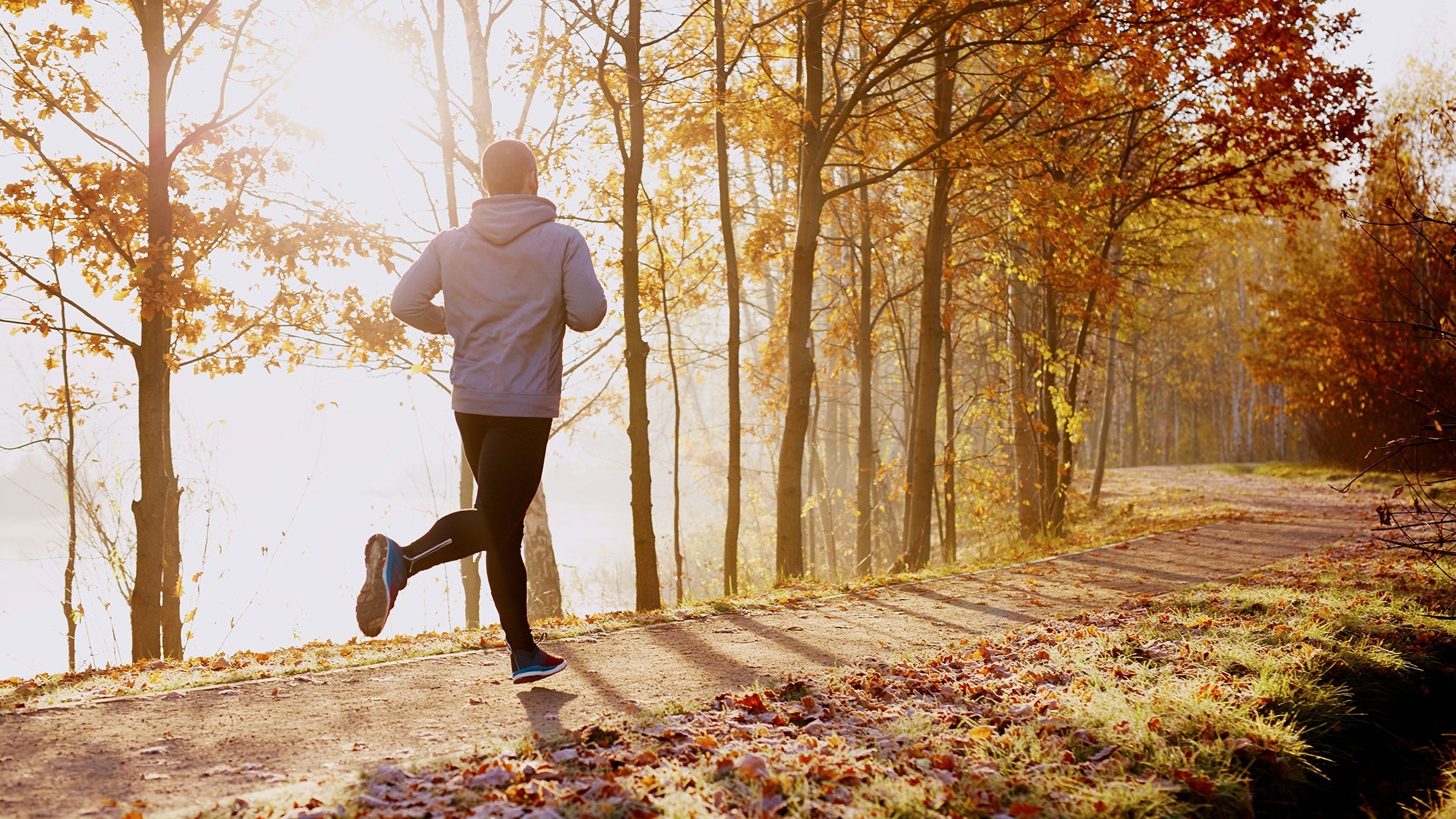 Man running next to lake in the fall